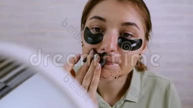 美颜护肤.. 女人在脸上涂眼底补丁。 洗面膜。 使用天然咖啡面罩，面部护理